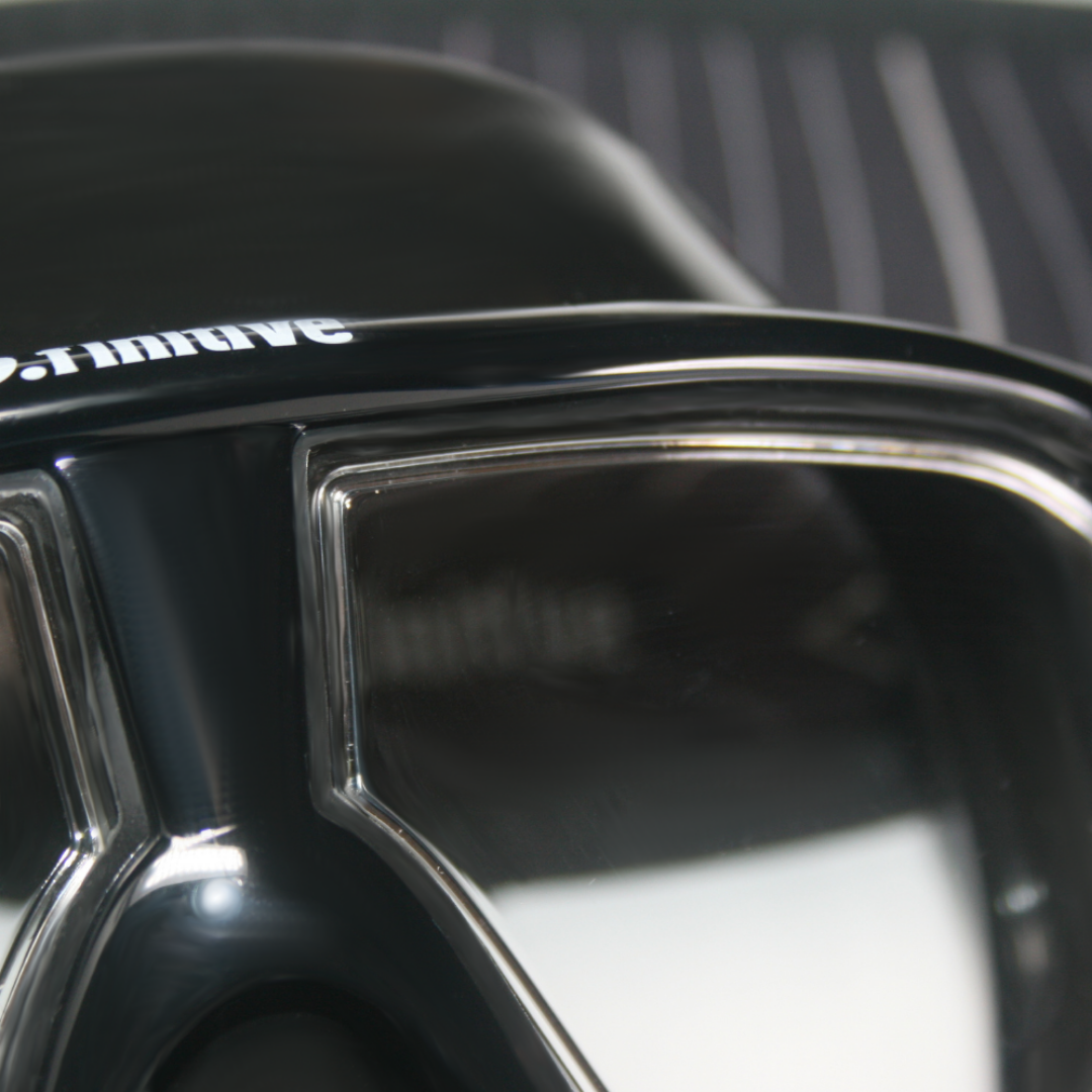 D.finitive Underwater Sports Mask - close up picture of a black underwater sports mask, with "D.finitive" written in white on the frame. The frame, lens and skirt are visible. Blue gradient background. Used for Underwater Hockey, Underwater Rugby and other underwater sports.